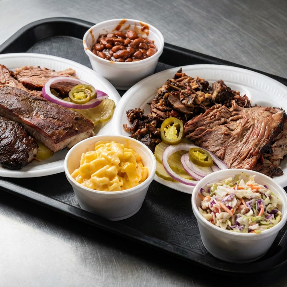 Barbecue platter with ribs, sliced brisket, pulled pork, baked beans, macaroni and cheese, and coleslaw garnished with pickles and onions.